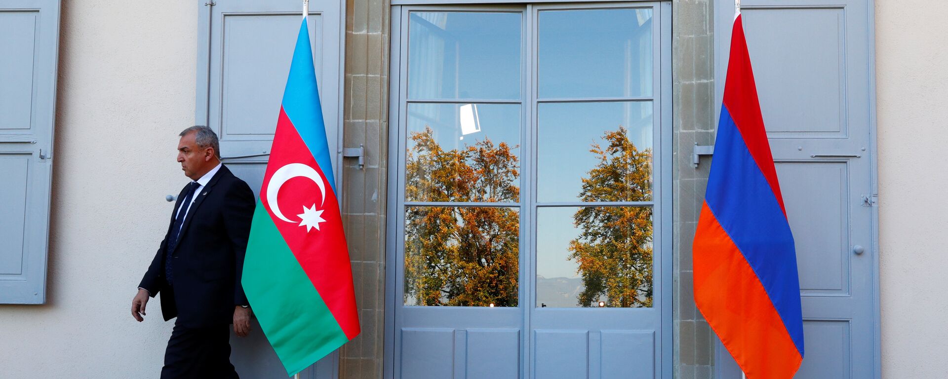 Охранник проходит мимо азербайджанского (слева) и армянского флага на открытии переговоров в Женеве, Швейцария - Sputnik Азербайджан, 1920, 23.10.2021