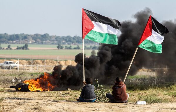 Палестинские демонстранты размахивают национальным флагом у границы между Израилем и Сектором Газа - Sputnik Азербайджан