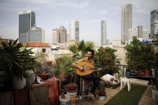 Музыкант Яр Шемель в своем саду на крыше, где он и два его товарища по квартире выращивают травы и овощи в Тель-Авиве, Израиль - Sputnik Азербайджан