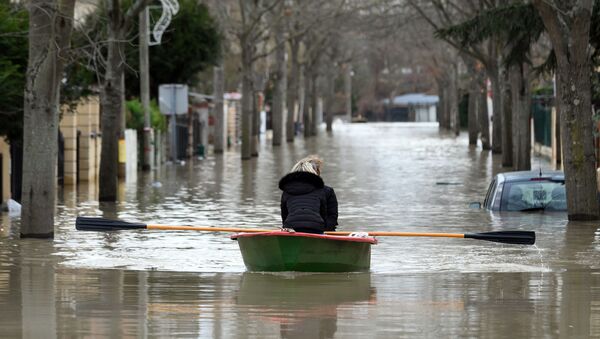 Местные жители переправляются на лодке на одной из затопленной улице в Париже - Sputnik Azərbaycan