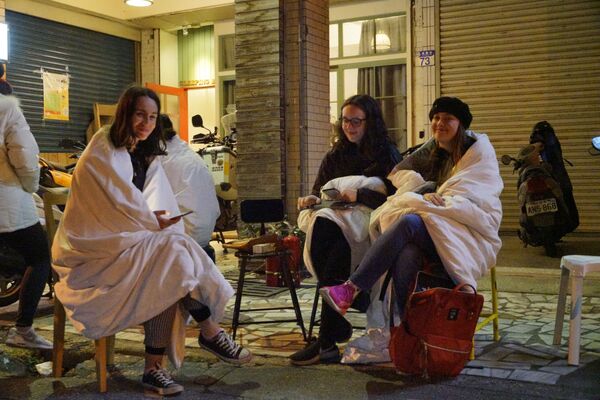 Британские туристы сидят на улице после мощного землетрясения в городе Хуалянь, Тайвань - Sputnik Азербайджан