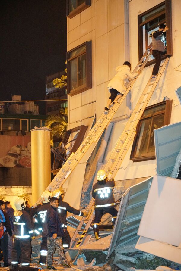 Женщины по пожарной лестнице покидают разрушенный в результате землетрясения в городе Хуалянь отель Marshal, Тайвань - Sputnik Азербайджан