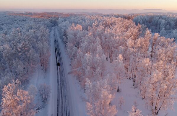 Машина едет по трассе вдоль заснеженного леса на закате, Красноярский край - Sputnik Азербайджан