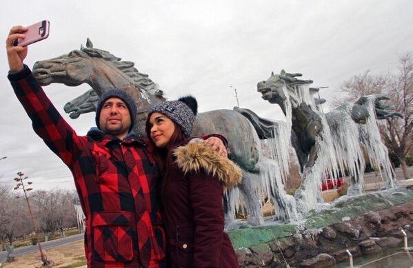 Пара делает селфи перед памятником, покрытым льдом, после похолодания в Сьюдад-Хуаресе, Мексика - Sputnik Азербайджан