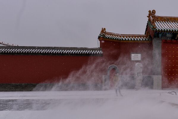 Китайский турист стоит у Императорского дворца во время снегопада в Шэньяне - Sputnik Азербайджан