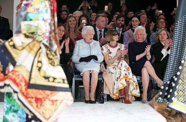 Britain's Queen Elizabeth II sits next to Vogue Editor-in-Chief Anna Wintour and Caroline Rush, Chief Executive of the British Fashion Council, and royal dressmaker Angela Kelly as they view Richard Quinn's runway show before presenting him with the inaugural Queen Elizabeth II Award for British Design as she visits London Fashion Week, in London, Britain February 20, 2018 - Sputnik Азербайджан