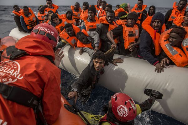 Спасение мигрантов сотрудниками испанской общественной организации Proactiva Open Arms с переполненной резиновой лодки у берегов Ливии - Sputnik Азербайджан