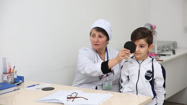 Врач проводит обследование школьника, фото из архива - Sputnik Азербайджан