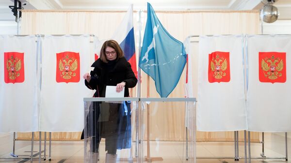Женщина опускает бюллетень в урну во время голосования на выборах президента Российской Федерации в Сахалинской области - Sputnik Азербайджан
