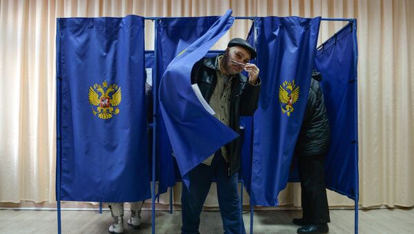 Мужчина выходит из кабинки во время голосования на выборах президента Российской Федерации на избирательном участке в Новосибирске - Sputnik Азербайджан