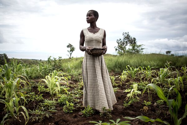 Женщина сеет семена в окрестностях временного лагеря для вынужденных переселенцев и репатриантов, Демократическая Республика Конго - Sputnik Азербайджан