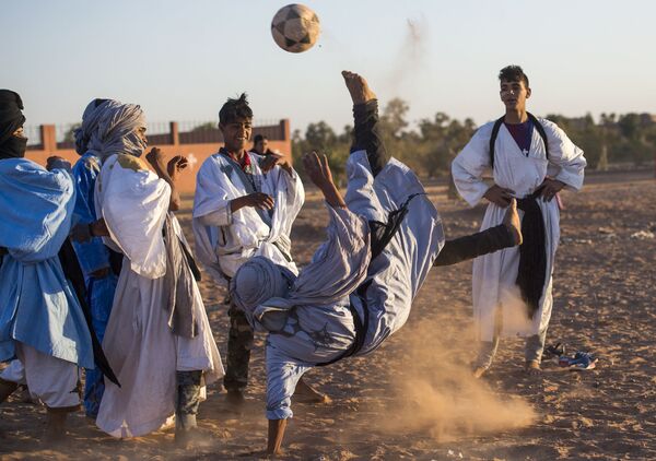 Подростки играют в футбол во время 15-го Международного фестиваля кочевников в Эль-Газлане в пустыне Сахара в Марокко - Sputnik Азербайджан