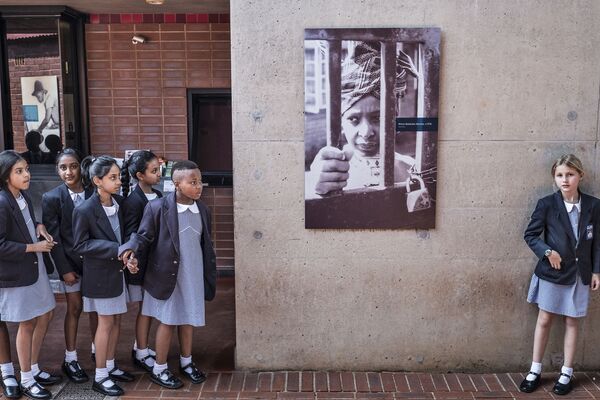 Южноафриканские школьницы рядом с плакатом, изображающим экс-жену Нельсона Манделы Винни на стене ее дома в Соуэто - Sputnik Азербайджан