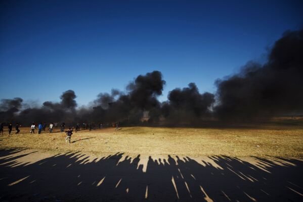 Палестинские протестующие во время столкновений с израильскими военными на границе сектора Газа и Израиля - Sputnik Азербайджан