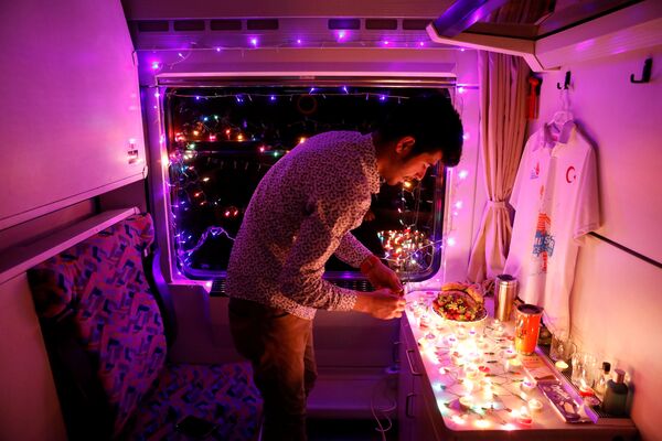 Молодой человек украшает свое купе Восточного экспресса свечами и гирляндами, Анкара - Карс, Турция - Sputnik Азербайджан