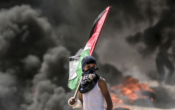 Палестинский демонстрант во время столкновений с израильскими силами у границы между сектором Газа и Израилем - Sputnik Азербайджан
