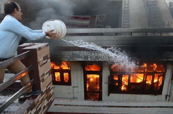 Мужчина пытается полушить пожар в магазине электротоваров в городе Амритсар, Индия - Sputnik Азербайджан