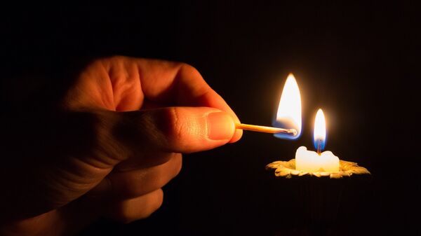 Человек зажигает свечу в темноте, фото из архива - Sputnik Азербайджан