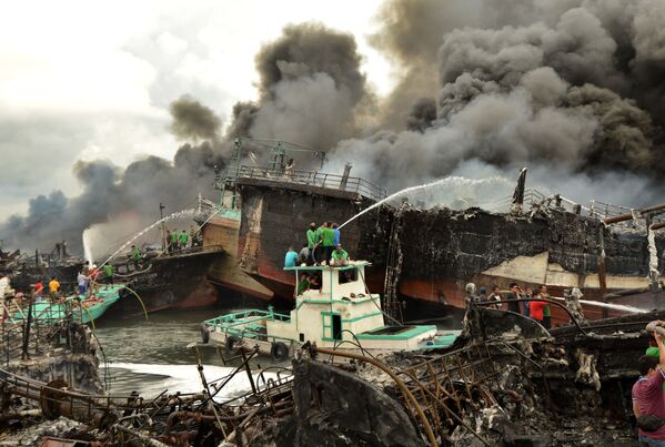 Рабочие и пожарные пытаются потушить горящие рыбацкие лодки в гавани Беноа, Денпасаре, Индонезия - Sputnik Азербайджан
