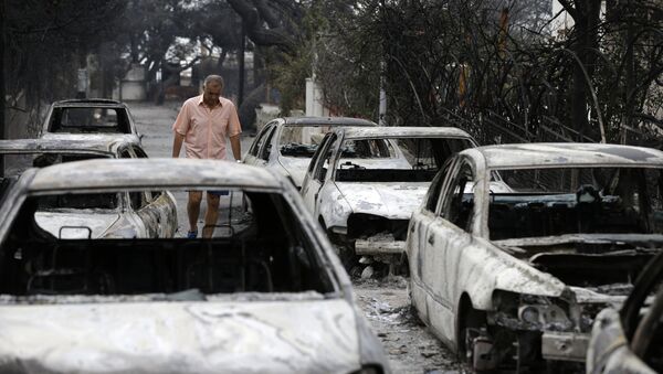 Мужчина среди сгоревших машин в Мати, к востоку от Афин, во вторник, 24 июля 2018 года - Sputnik Azərbaycan