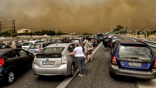 Люди рядом со своими автомобилями на закрытой дороге рядом с зоной лесных пожаров в греческой деревне Кинета - Sputnik Azərbaycan