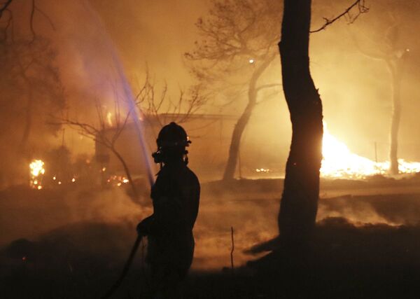 Пожарный в зоне лесного пожара к востоку от Афин - Sputnik Азербайджан