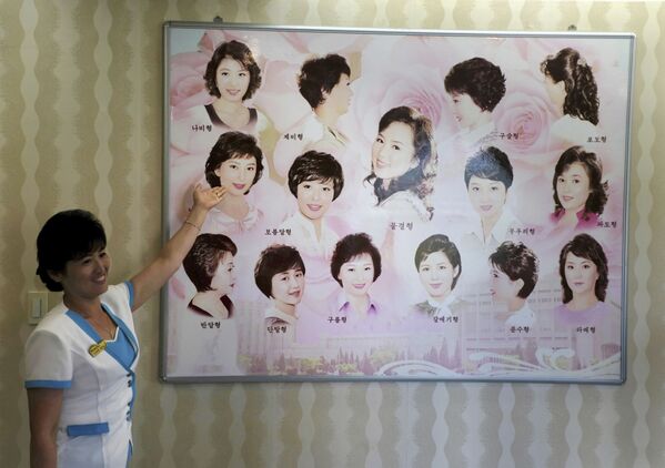 Гид показывает плакат с женскими прическами в парикмахерской Пхеньяна, Северная Корея - Sputnik Азербайджан