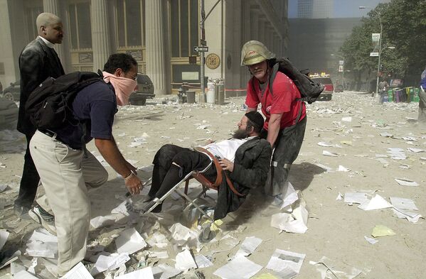 Спасатели эвакуируют мужчину после обрушения одной из башен Всемирного торгового центра 11 сентября 2001 года в Нью-Йорке, США - Sputnik Азербайджан