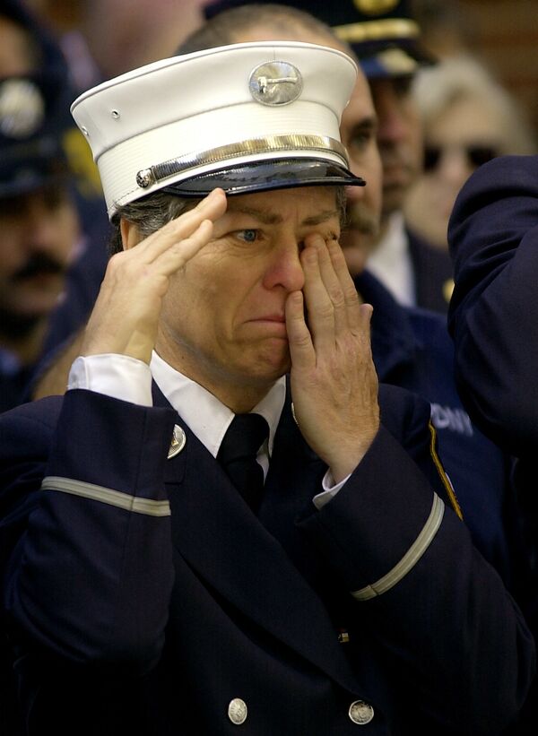 Неизвестный пожарный утирает слезу, когда он отдает честь капеллану отдела пожарной безопасности Нью-Йорка - жертве теракта 11 сентября 2001 года - Sputnik Азербайджан