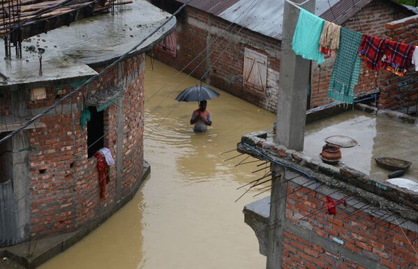 Мужчина посреди затопленной улицы индийского города Силигури - Sputnik Азербайджан