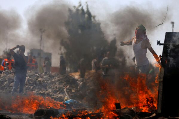 Палестинские демонстранты бросают камни в израильских военных во время протестов против планов снести бедуинскую деревню Khan al-Ahmar рядом с израильским поселением Бейт-Эль - Sputnik Азербайджан
