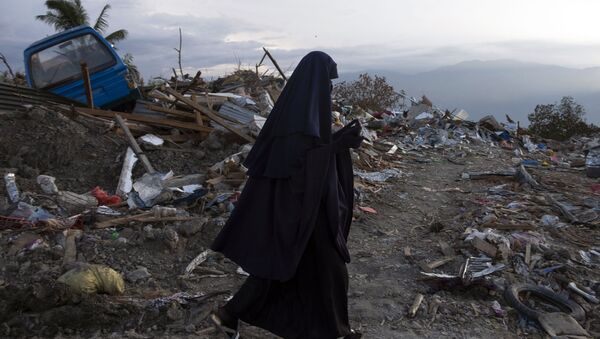 Индонезийская женщина идет мимо завалов мусора в деревне Петбо в Палу, оставшихся после землетрясения и цунами, произошедших 28 сентября - Sputnik Азербайджан