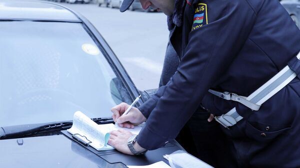 Сотрудник дорожной полиции составляет протокол об административном правонарушении, фото из архива - Sputnik Azərbaycan