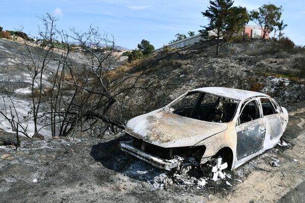 Автомобиль, сгоревший в результате лесных пожаров, в окрестностях города Малибу в штате Калифорния - Sputnik Азербайджан