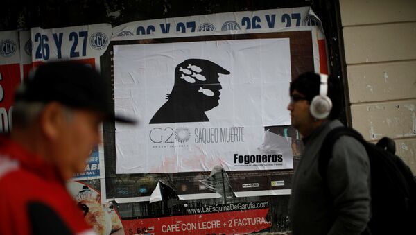 Пешеходы проходят мимо знака с надписью G20, грабежи, смерть с изображением президента США Дональда Трампа на улице Буэнос-Айреса, Аргентина 1 декабря - Sputnik Азербайджан