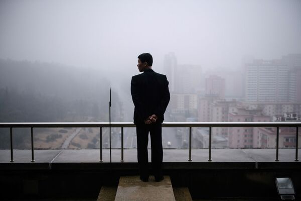 Мужчина на балконе дома в Пхеньяне в туманный день - Sputnik Азербайджан