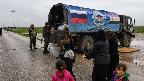 Сирийские гражданские лица проезжают мимо российского военного грузовика с продовольственной помощью - Sputnik Азербайджан