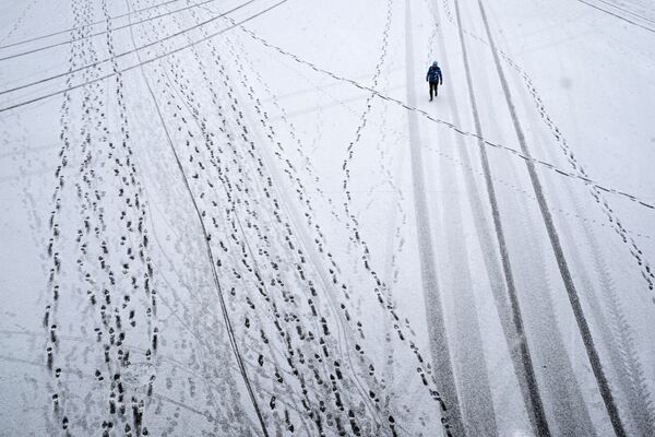 Прохожий во время снегопада в Парке Горького в Москве - Sputnik Азербайджан