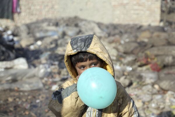 Афганский мальчик надувает воздушный шарик, окраина Кабула, Афганистан, 2017 год - Sputnik Азербайджан
