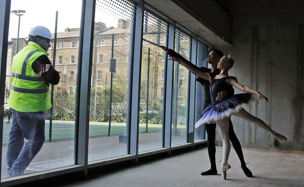 Рабочий за стеклом наблюдает за артистами в Центральной школе балета в Лондоне - Sputnik Азербайджан