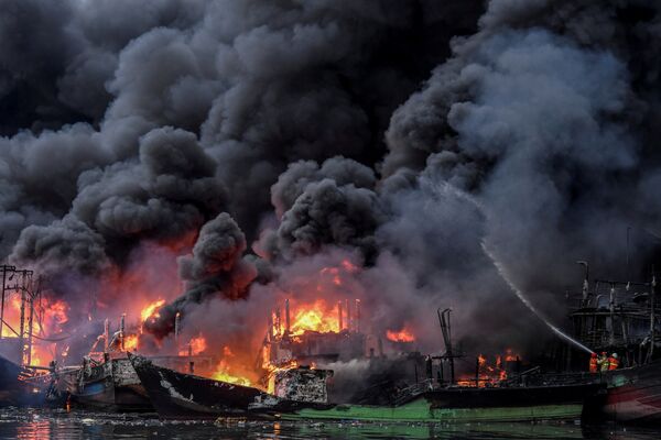 Пожарные тушат горящие рыбацкие лодки в порту Муара Бару в Джакарте, Индонезия - Sputnik Азербайджан