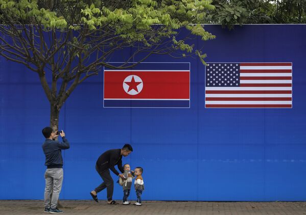 Жители Ханоя позируют перед изображением северокорейского и американского флага в дни прохождения саммита КНДР-США в Ханое - Sputnik Азербайджан