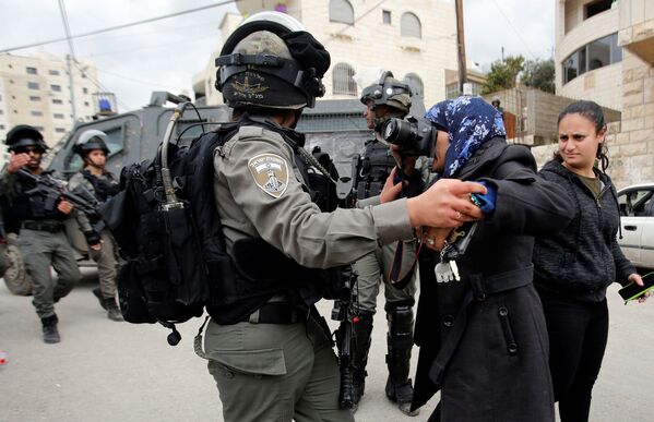 Женщина фотографирует израильского пограничника во время сноса палестинского дома, хозяева которого не оформили лицензии на строительство, в палестинском городе Бейт-Джала на территории Западного Берега Реки Иордан - Sputnik Азербайджан