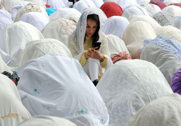 Мусульманка с мобильным телефоном среди молящихся во время празднования Ид аль-адха в Джакарте - Sputnik Азербайджан