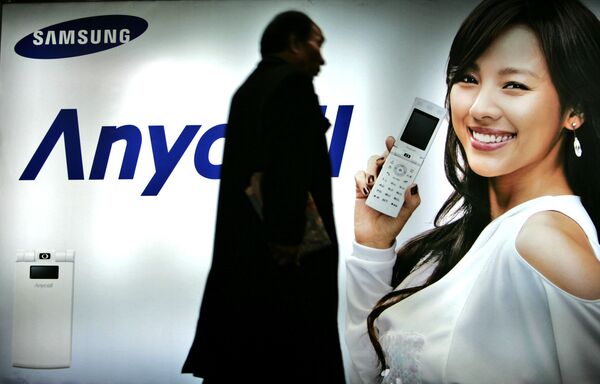 Пешеход идет мимо рекламного щита Samsung Mobile в Сеуле, Южная Корея. 2007 год - Sputnik Азербайджан