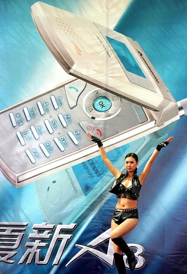 Танцовщица рядом с рекламным баннером нового мобильного телефона в китайском городе Чунцин, 2002 год - Sputnik Азербайджан