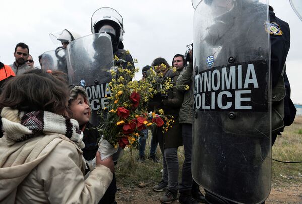 Дети дарят цветы сотрудникам греческой полиции после столкновений у лагеря беженцев в Диавате, Греция - Sputnik Азербайджан