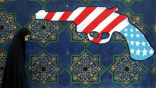Девушка в хиджабе проходит мимо фрески с изображением пистолета с американским флагом на стене бывшего посольства США в Тегеране  - Sputnik Азербайджан