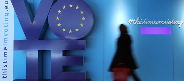 Женщина проходит мимо рекламного щита о выборах в ЕС на железнодорожной станции Шуман возле Европейского парламента в Брюсселе - Sputnik Азербайджан