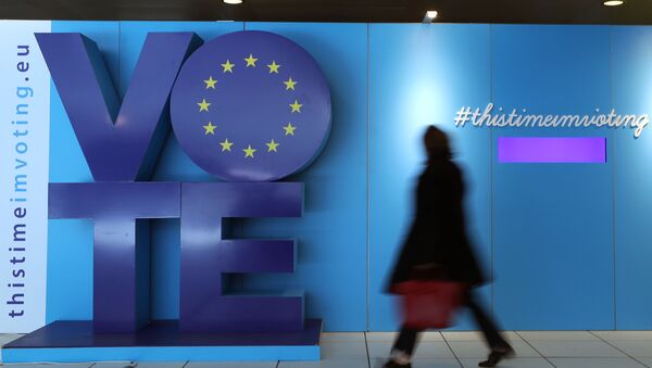 Женщина проходит мимо рекламного щита о выборах в ЕС на железнодорожной станции Шуман возле Европейского парламента в Брюсселе - Sputnik Азербайджан